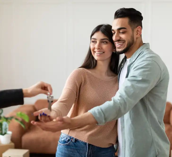 Reading real estate agent giving keys to excited buyers
